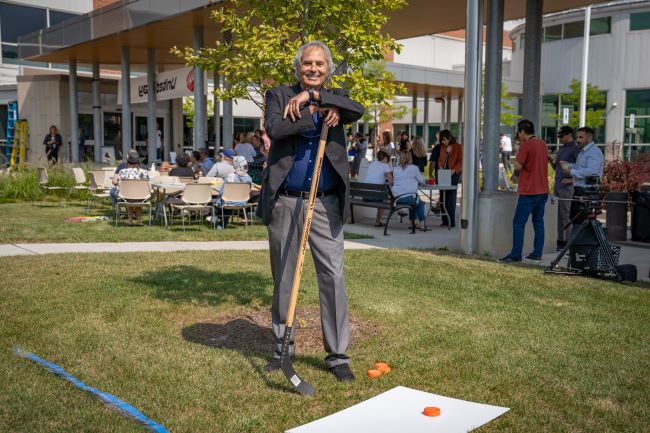 Regional Chair Gary Carr holding a hockey stick at a fundraiser event station.