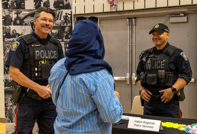Halton Regional Police officers speak with a person at their information table during the job fair.