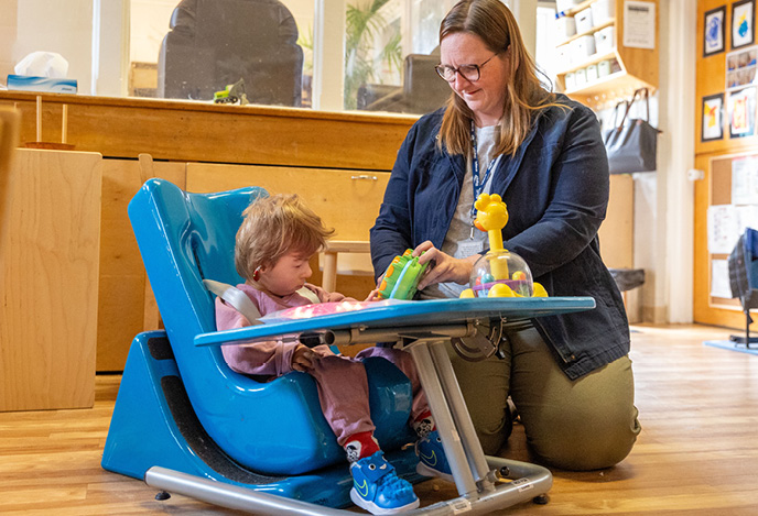 A child care worker playing with a child at an activity station.