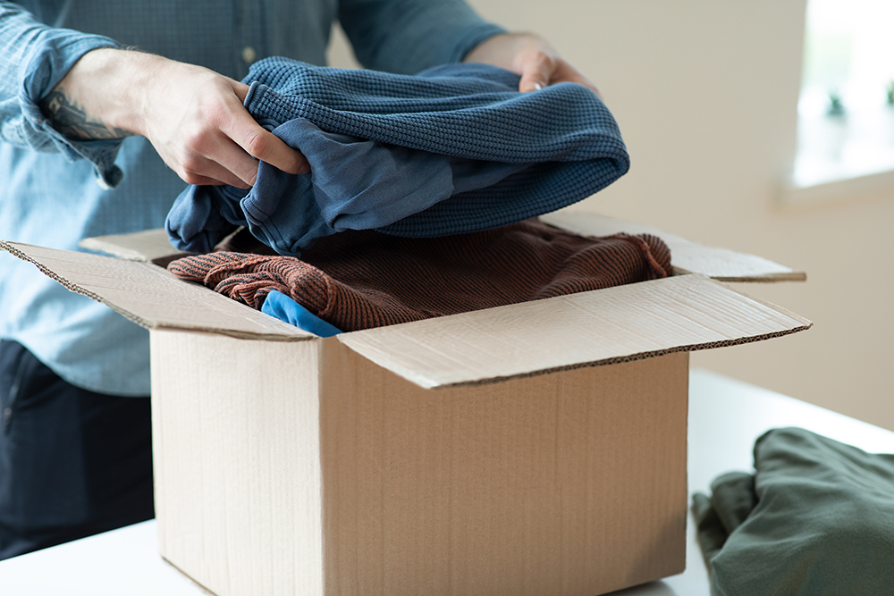 person putting clothes into box