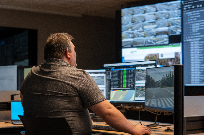 A man seated in front of a cluster of screens.