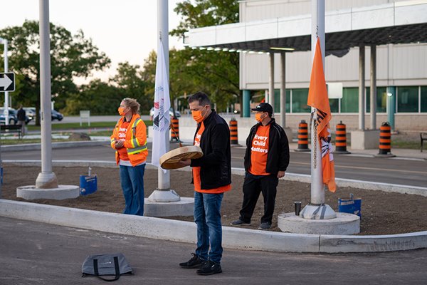 Image of Eddy Robinson and two others in orange shirts during the flag ceremony
