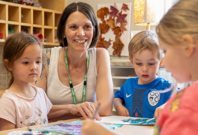 Early childhood educator at a table with children