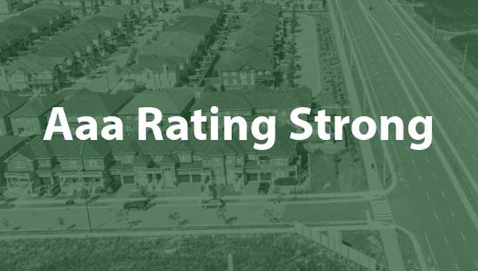 A drone photo of the community with the text "Aaa Rating Strong" superimposed.