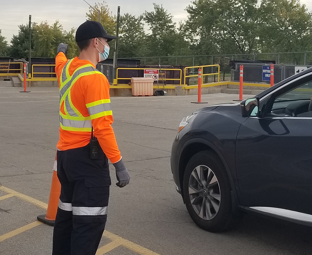 worker directing car where to drop off waste items