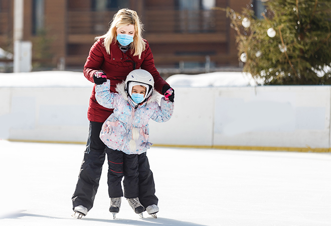 mother and daughter ice skating on an outdoor rink