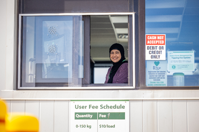 A woman seated at an outdoor welcome structure.