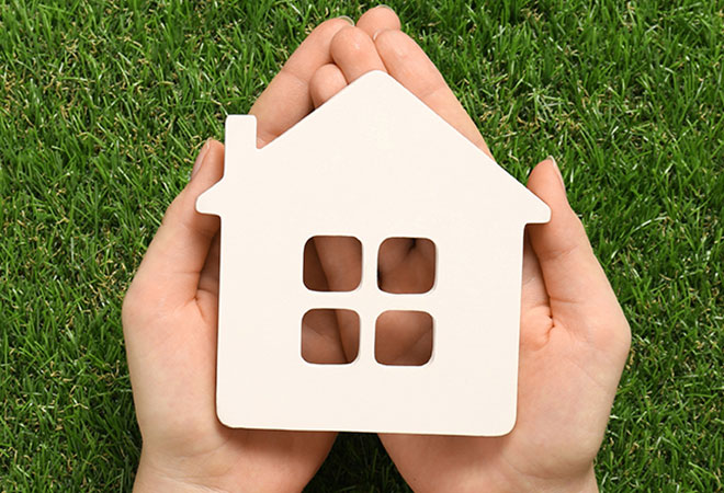 cut-out of a house resting in the palms of someones hands.