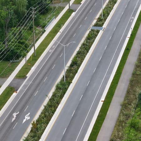 An aerial view of a 4-lane roadway with separated sidewalks separated by a median.
