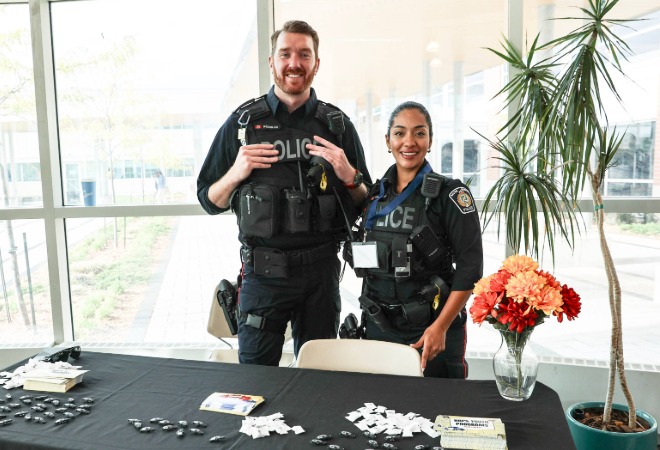 Two smiling police officers standing behind a display.