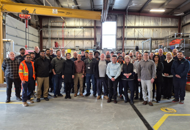 A group of adults inside a large mechanical facility.