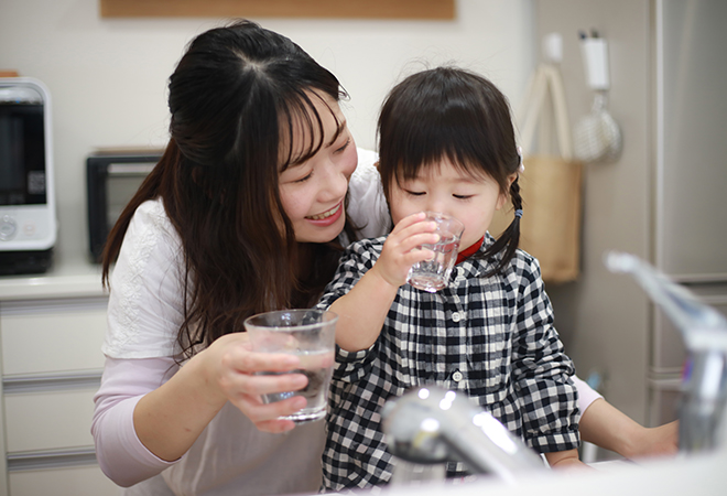 mother and daughter drinking water in the kitchen