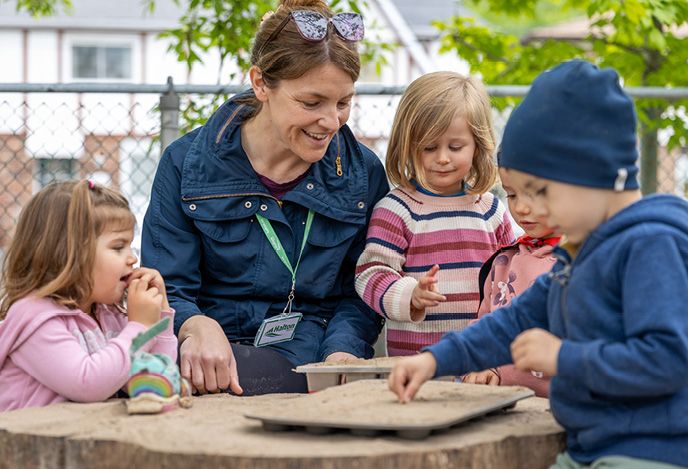 A child care worker teaching children outdoors.